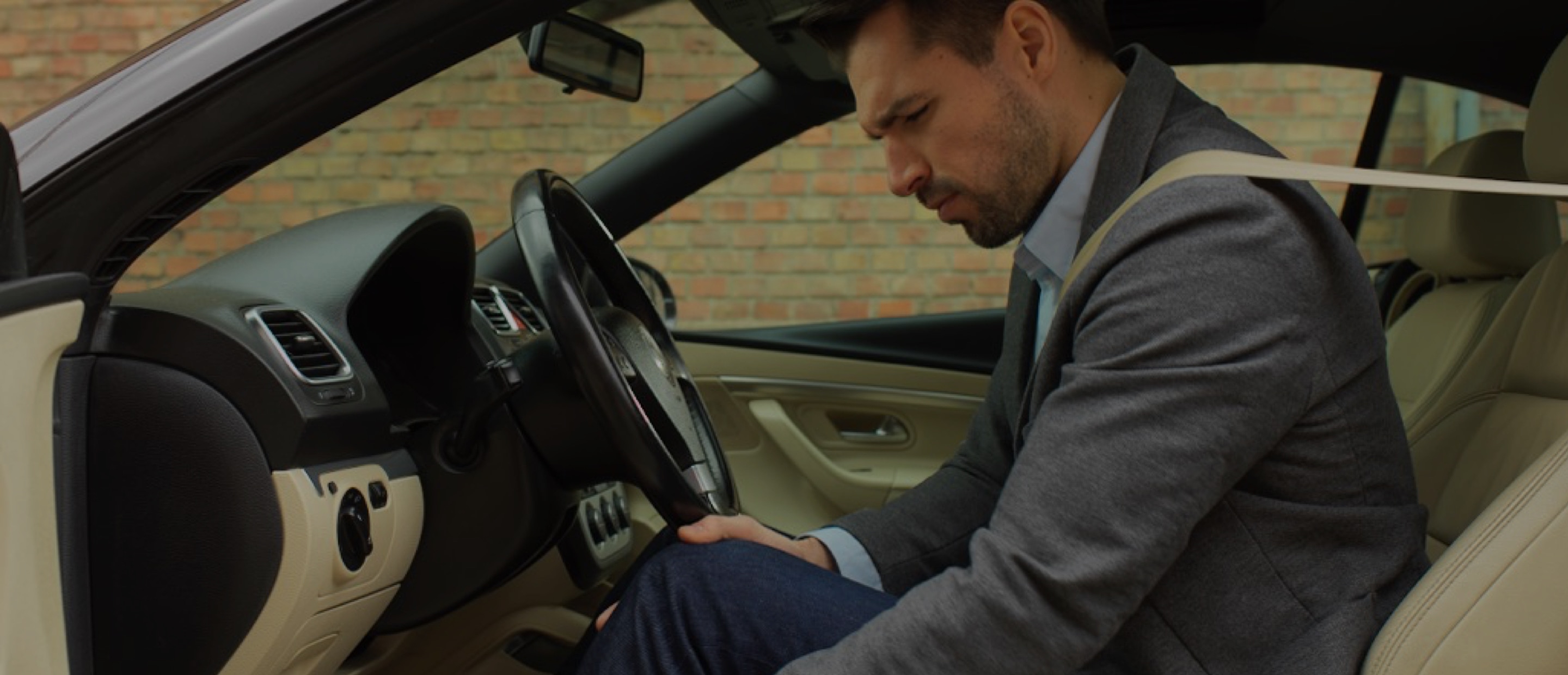 Muškarac s osjećajem težine u nogama sjedi u automobilu